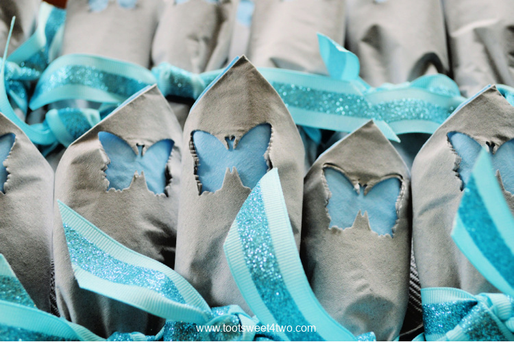 close-up of gray paper napkins with blue butterfly cut-out tied with blue ribbon