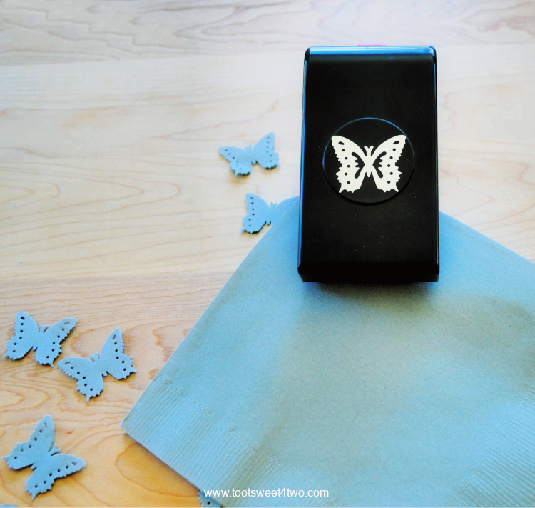 punching out butterfly shapes on a blue napkin