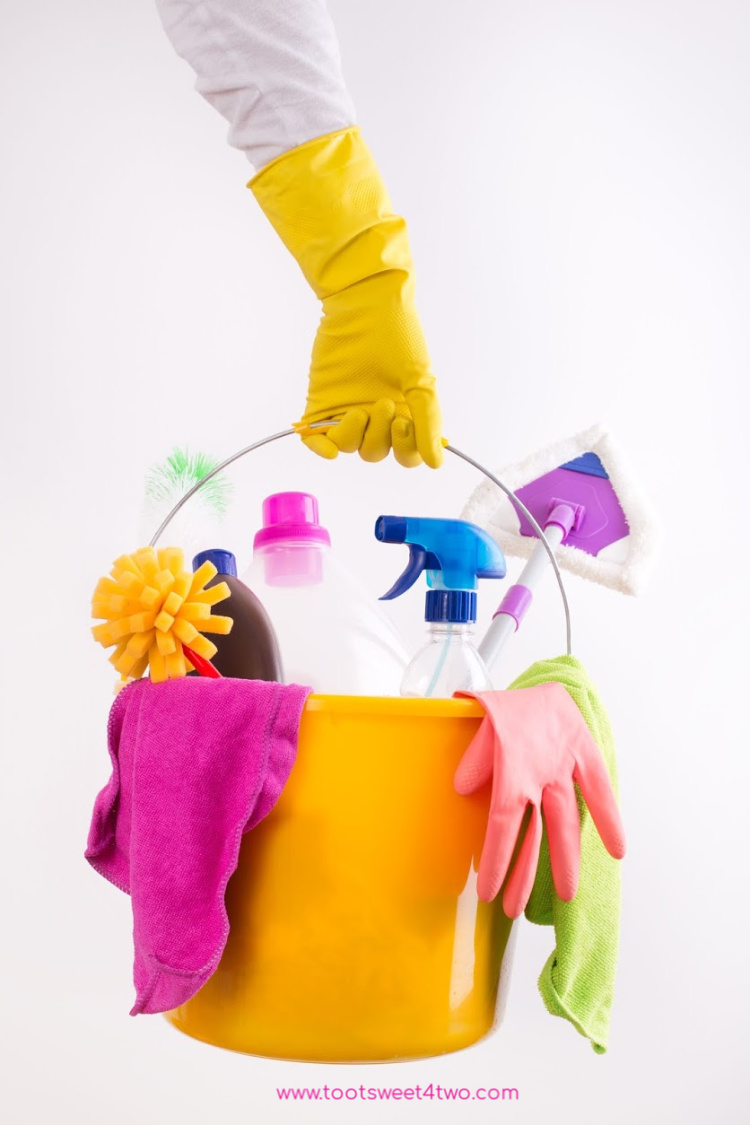 woman's hand carrying a bucket full of cleaning supplies