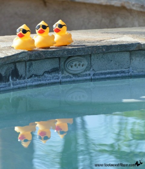 Yellow duckies with sunglasses reflected in the pool