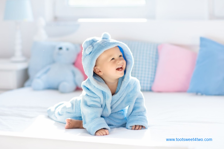 baby boy in blue hooded bathrobe on bed after a bath