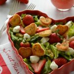 Green salad with strawberries in heart-shaped bowl with mini-heart croutons and pink dressing