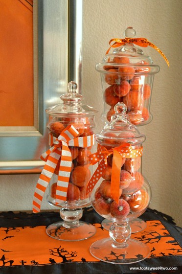 Mini faux pumpkins stacked inside glass jars