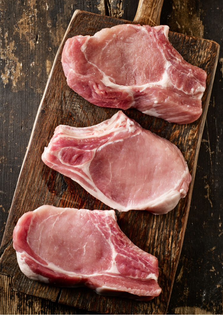 fresh raw pork chops on old wooden cutting board