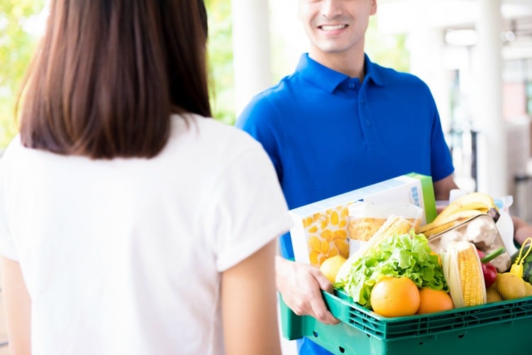Delivery man delivering food to a woman - online grocery shopping service concept