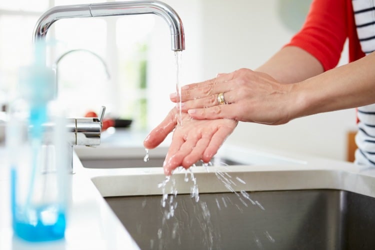 Close Up Of Woman Washing Hands In Kitchen Sink