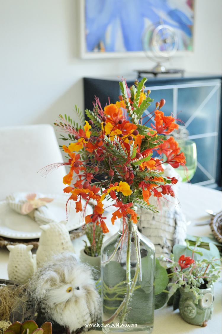 owl table decor with red bird of paradise flowers on a dining table